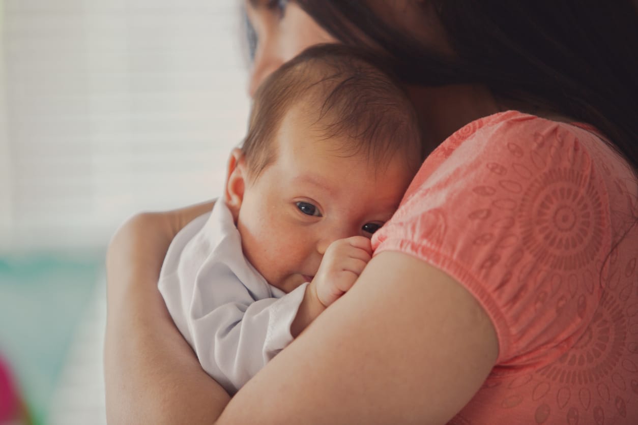 Close up of little baby girl on mother's shoulder.